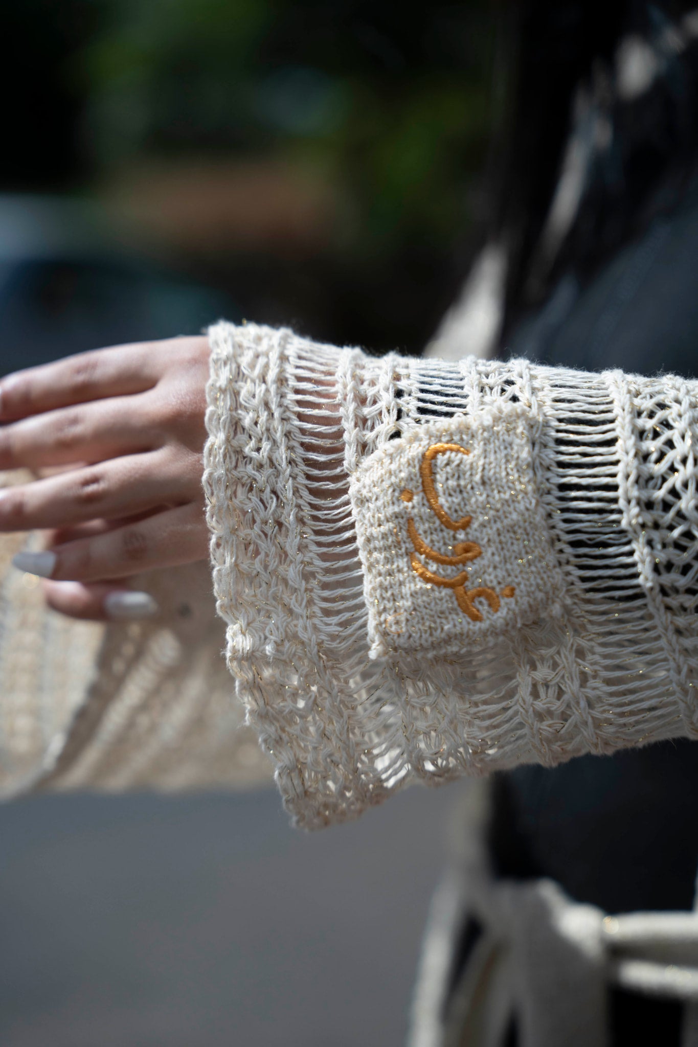 Ghoroub Cardigan in Sunset Ivory · Gold, close-up of the embroidered cuff detail.